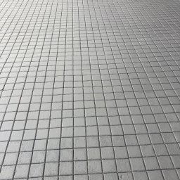 Jarek Wachowiak - Szara kostka brukowa ułożona w regularny wzór, widok z góry, lekka perspektywa, czysta powierzchnia, fuga podkreślona cieniem.