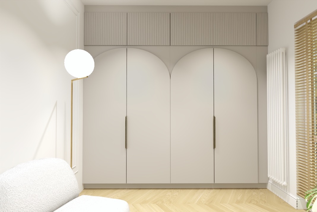 Wnętrze pokoju z dużą, czterodrzwiową szafą wnękową o zaokrąglonych górnych krawędziach, szare fronty, długie, pionowe uchwyty, nad szafą panele z pionowymi żłobieniami, obok biały grzejnik i okno...