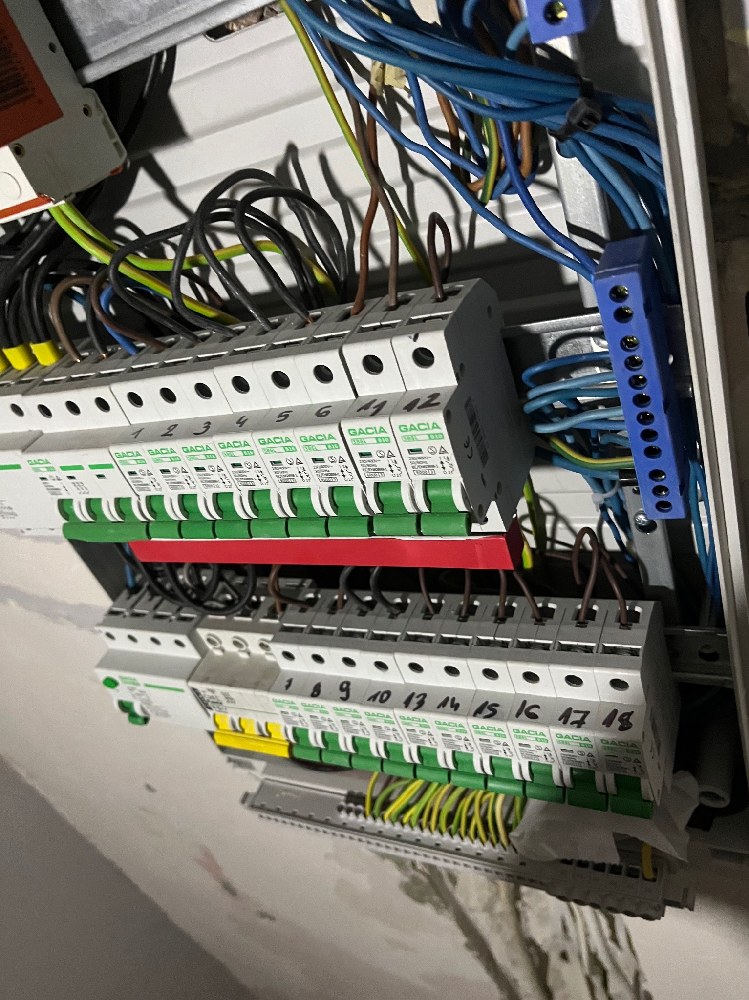 Rozdzielnica elektryczna z przewodami i bezpiecznikami, widok z bliska. Instalacja w trakcie prac, z numeracją bezpieczników.