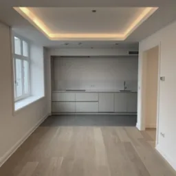 Nowoczesne wnętrze mieszkania po remoncie: parkiet w odcieniach szarości, białe ściany z listwami przypodłogowymi, minimalistyczna kuchnia w tle z szarymi frontami szafek i blatem, sufit...