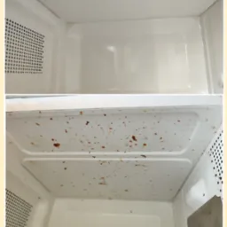 Mikrofalówka przed i po czyszczeniu: wnętrze z resztkami jedzenia (dół) i czyste, białe wnętrze (góra). Widoczne otwory wentylacyjne po lewej stronie.