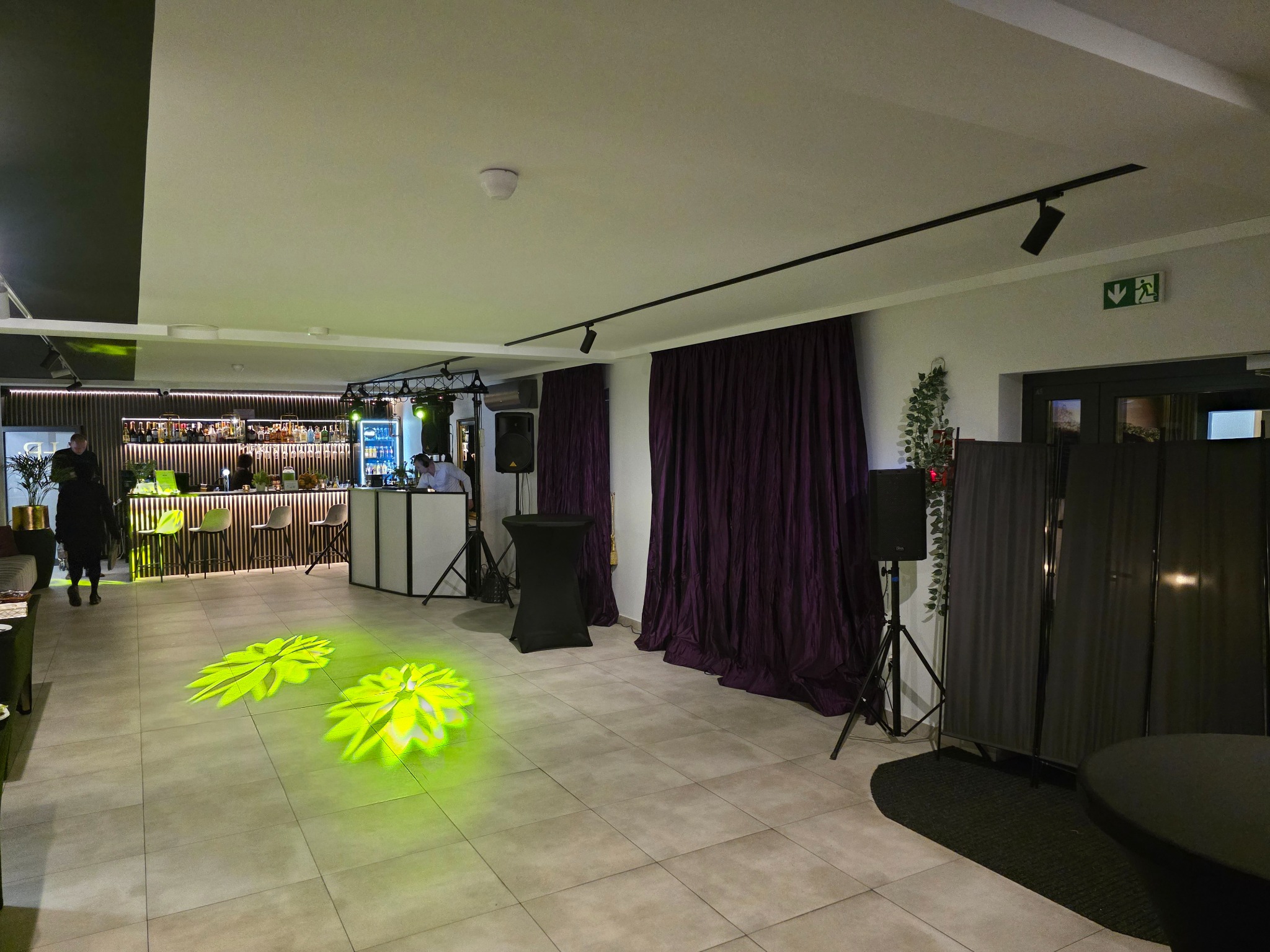 Sala bankietowa przygotowana na imprezę: bar z oświetleniem, stanowisko DJ-a, nagłośnienie i dekoracyjne światła na podłodze.