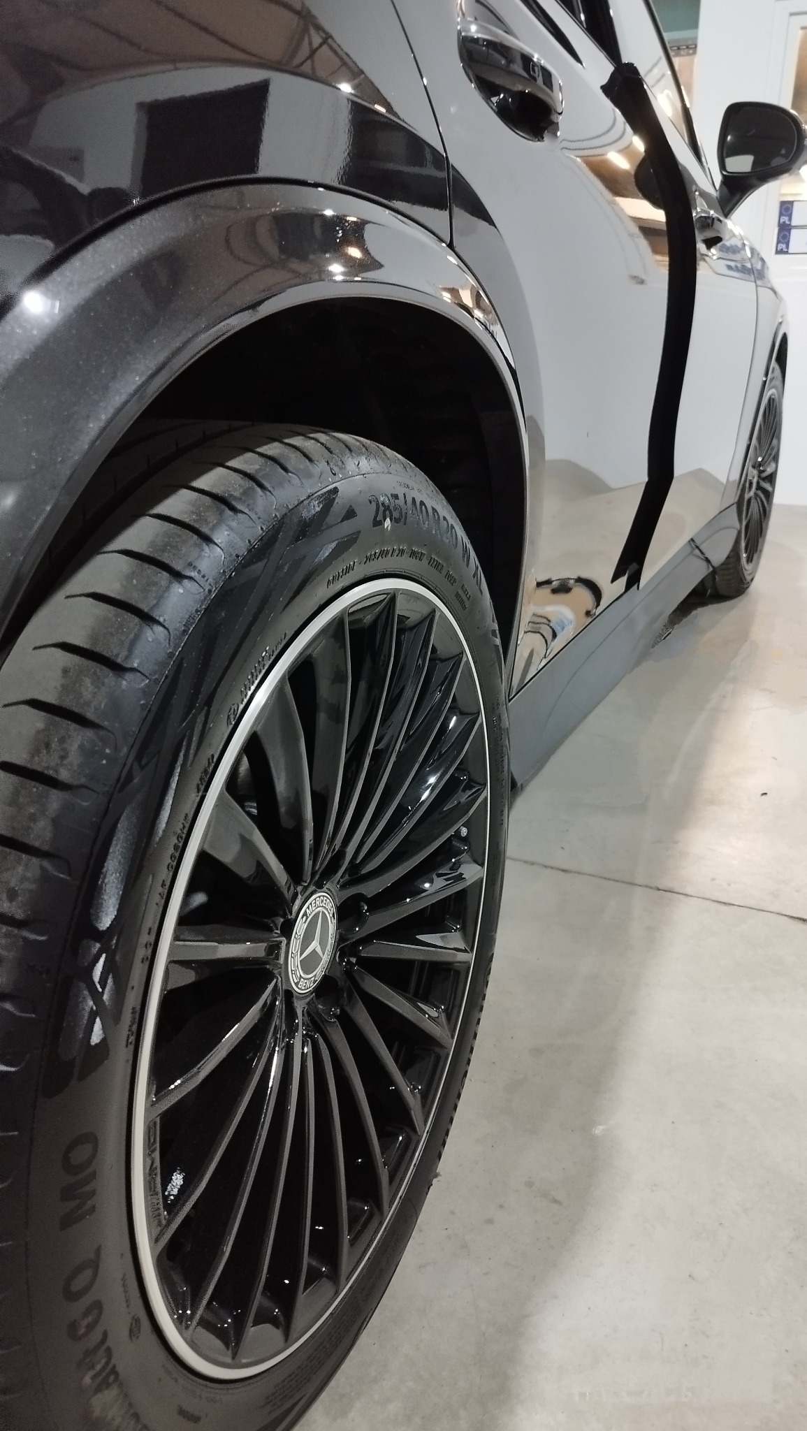 Błyszczący, czarny samochód marki Mercedes z aluminiowymi felgami o skomplikowanym wzorze, widoczne oznaczenia opony 285/40 R20