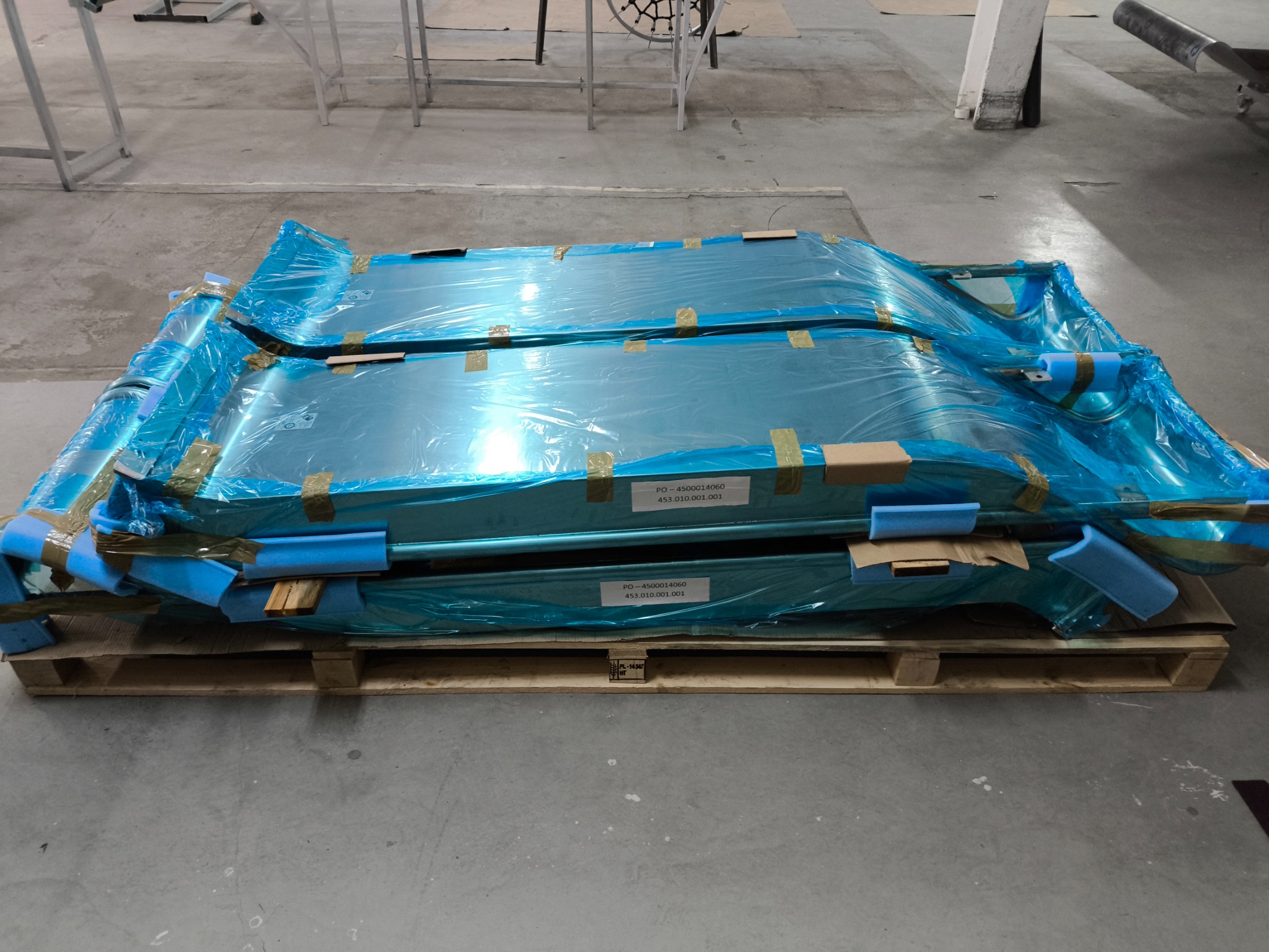 Gotowe elementy metalowe zabezpieczone folią i pianką na palecie, przygotowane do transportu.