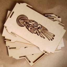 PRUS CAPITAL SPÓŁKA Z OGRANICZONĄ ODPOWIEDZIALNOŚCIĄ - Stos drewnianych, wyciętych laserowo elementów z motywem stylizowanej postaci anioła, przygotowanych do złożenia w pudełko lub ozdobę.