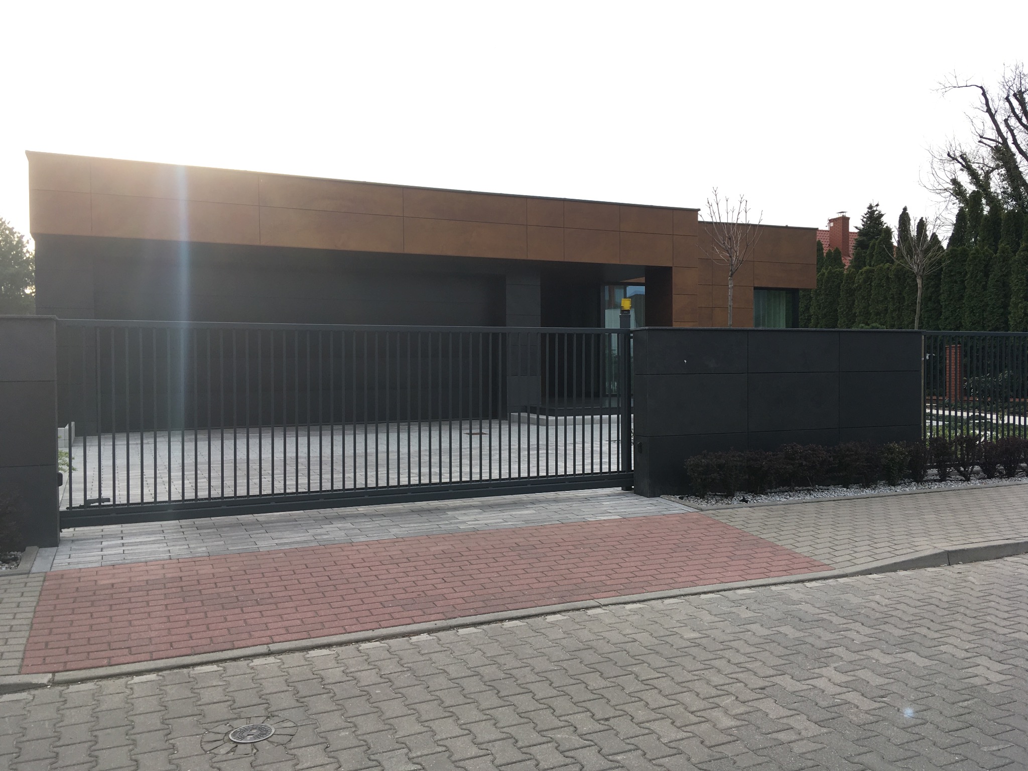 Elewacja domu, ogrodzenie i altana śmietnikowa z kamienia Łupek i HPL Prodema. System klejony Bostik