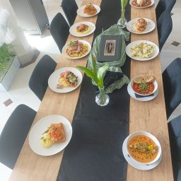 Ludowa - Elegancko zastawiony stół z różnorodnymi daniami, dekoracjami kwiatowymi i czarnym bieżnikiem, gotowy na przyjęcie gości. Widok z góry.