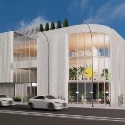 MAP Projekt - Wizualizacja nowoczesnego, białego budynku biurowego z dużymi oknami, roślinami wewnątrz i przejeżdżającym tramwajem. Budynek ma zaokrąglony narożnik i płaski dach.