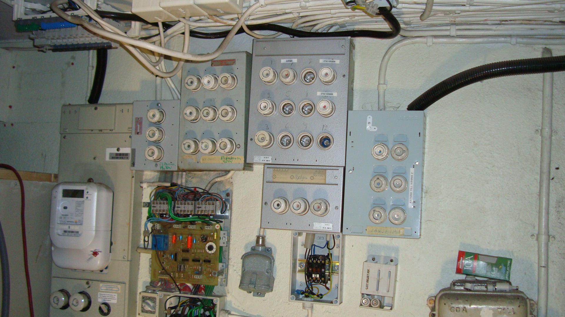 Stara tablica bezpiecznikowa z bezpiecznikami topikowymi, licznik energii elektrycznej i przewody w instalacji elektrycznej w Łodzi.