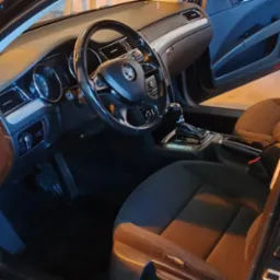 Wnętrze samochodu marki Skoda z otwartymi drzwiami, widoczna deska rozdzielcza, kierownica, fotele i dywaniki.