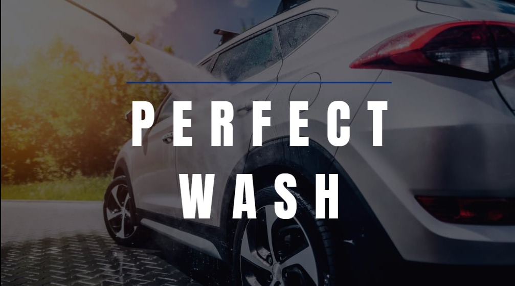 Szary SUV myty pod ciśnieniem na zewnątrz w słoneczny dzień, widoczne krople wody i mokra nawierzchnia.