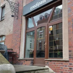 Wejście do biura Credipass w kamienicy ze schodami i szyldem nad drzwiami.