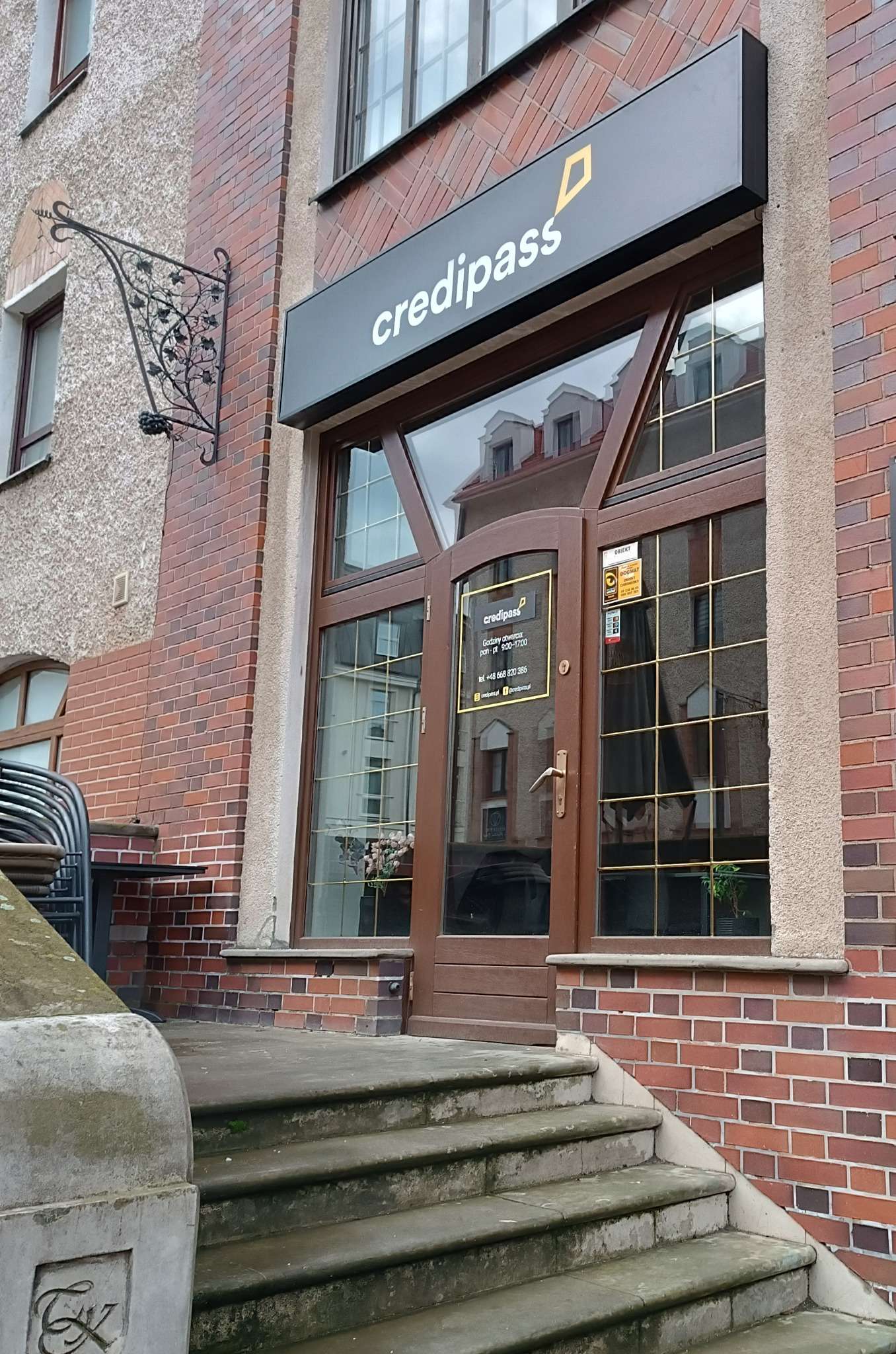 Wejście do biura Credipass w kamienicy ze schodami i szyldem nad drzwiami.