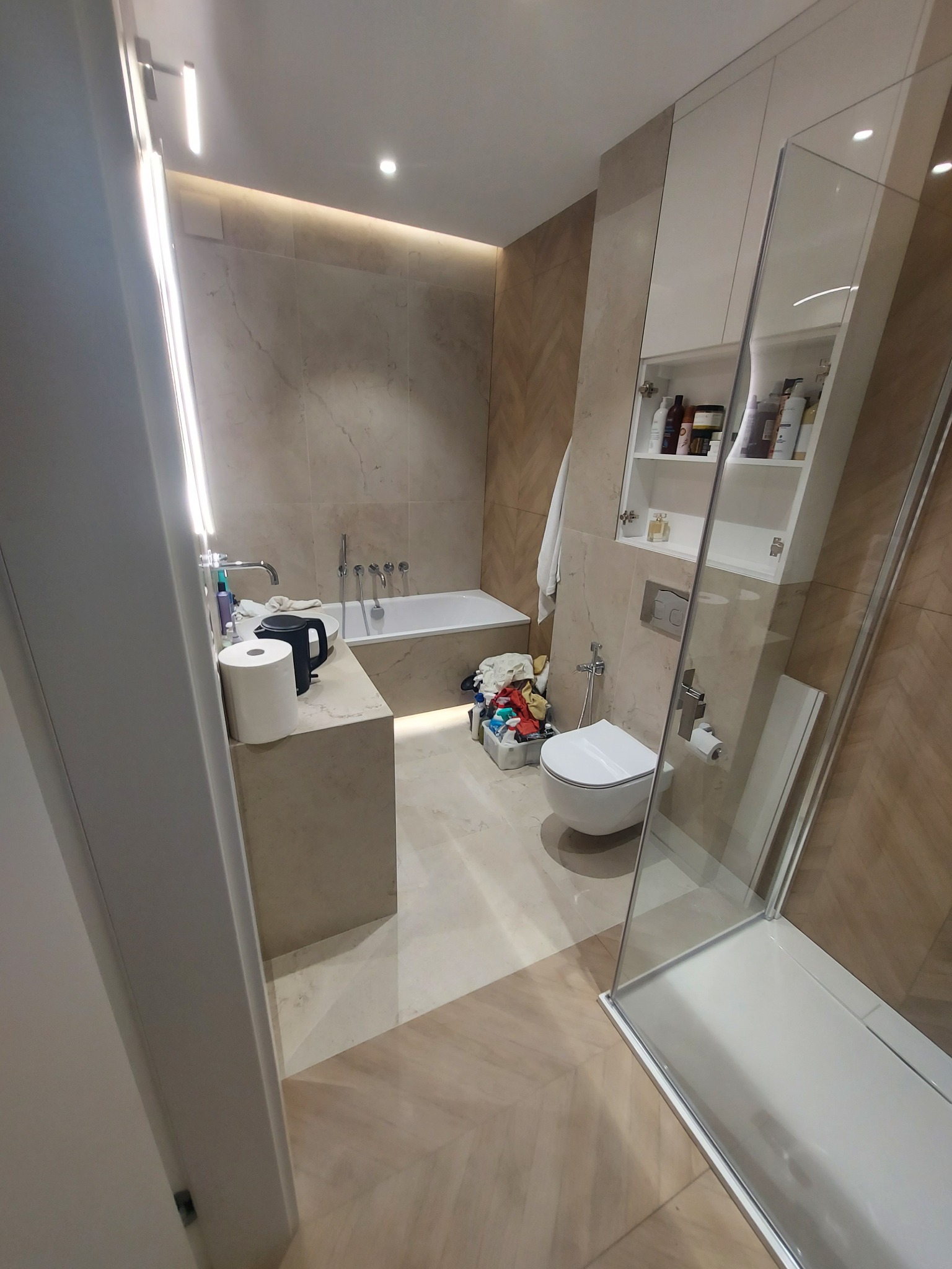 Wykończona łazienka w Lublinie z beżowymi płytkami, wanną, kabiną prysznicową i toaletą. Widoczne białe szafki i armatura. Nowoczesny design z oświetleniem LED.