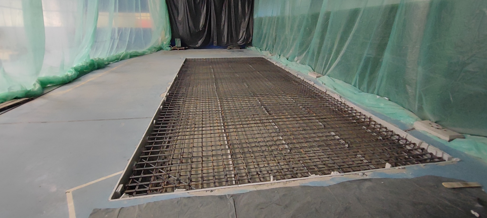 Zbrojenie ułożone w przygotowanym wykopie, zabezpieczone folią budowlaną na ścianach, gotowe do zalania betonem.