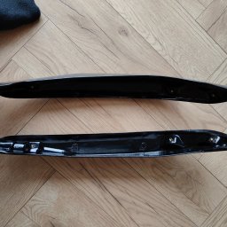 B3Ddesign.pl - Dwie czarne, błyszczące osłony z tworzywa na drewnianej podłodze. Widoczne otwory montażowe i odbicia światła podkreślające gładką powierzchnię.