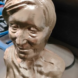 B3Ddesign.pl - Złoty, pomalowany popiersie kobiety, wydrukowane w technologii FDM. Widoczne warstwy druku. W tle maszyna i karton.