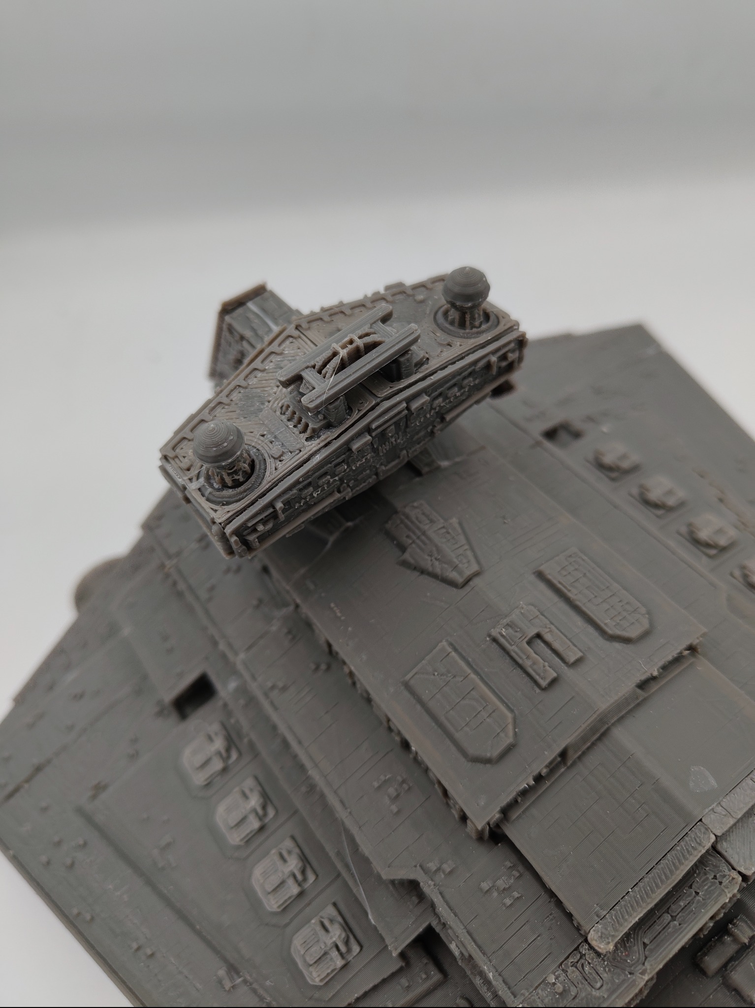 Szary model statku kosmicznego z widocznymi detalami, wydrukowany w technologii 3D. Na górze mniejszy statek. Widoczne warstwy druku.