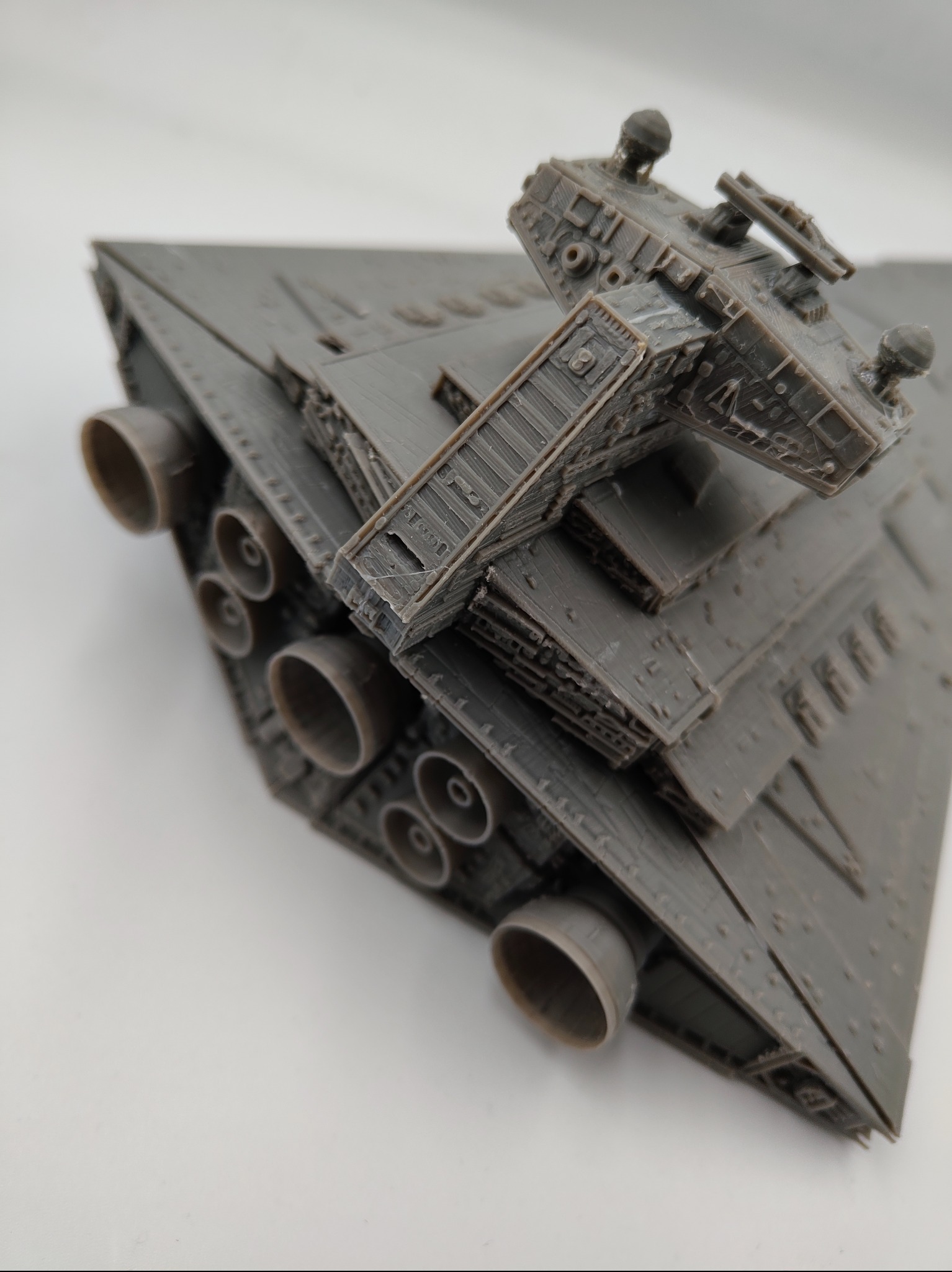 Szary model gwiezdnego niszczyciela wydrukowany w 3D, z widocznymi detalami dysz silnikowych i wieżyczki. Model na białym tle, oświetlenie studyjne.