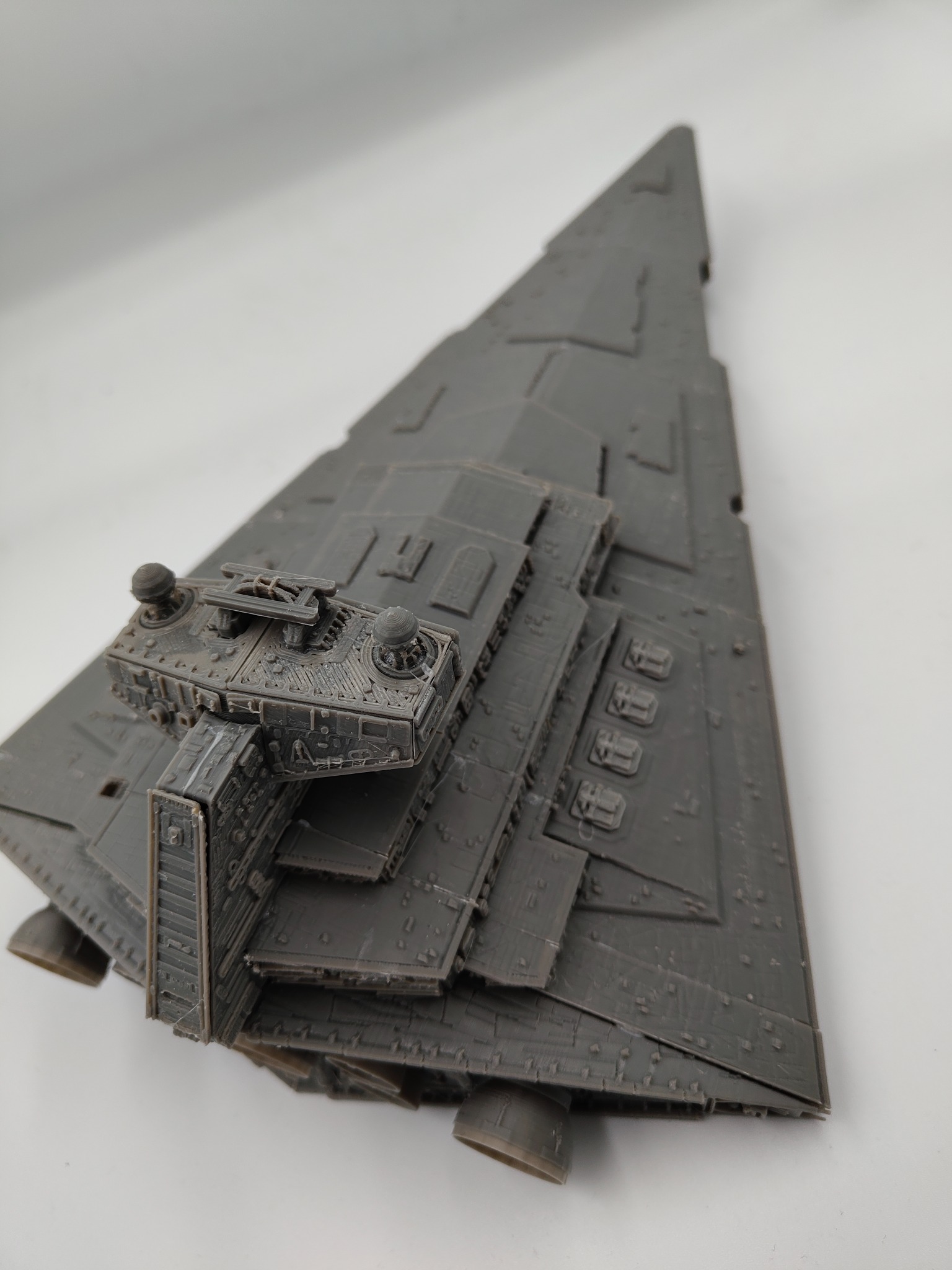 Szary model gwiezdnego niszczyciela z detalami, wydrukowany w 3D, leżący na białym tle. Widoczne warstwy druku i szczegółowe elementy konstrukcyjne.