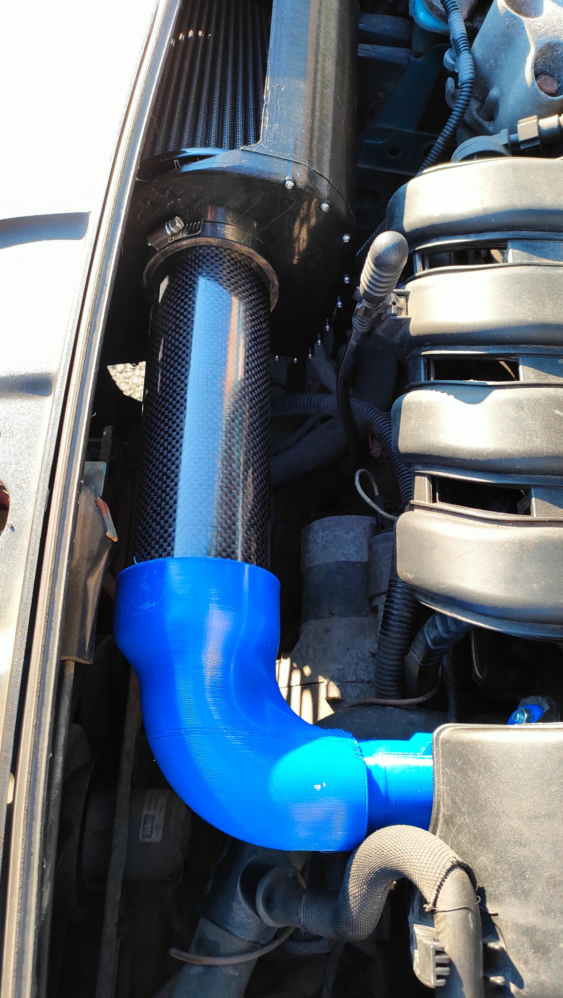 Customowy dolot powietrza z włókna węglowego i niebieskiego poliuretanu, zamontowany w samochodzie. Wykonanie FDM, Gdańsk. Unikalny projekt.