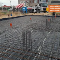 Zbrojenie płyty fundamentowej przygotowane do zalania betonem w Ożarowie Mazowieckim, widoczny betonowóz i poziomica laserowa.