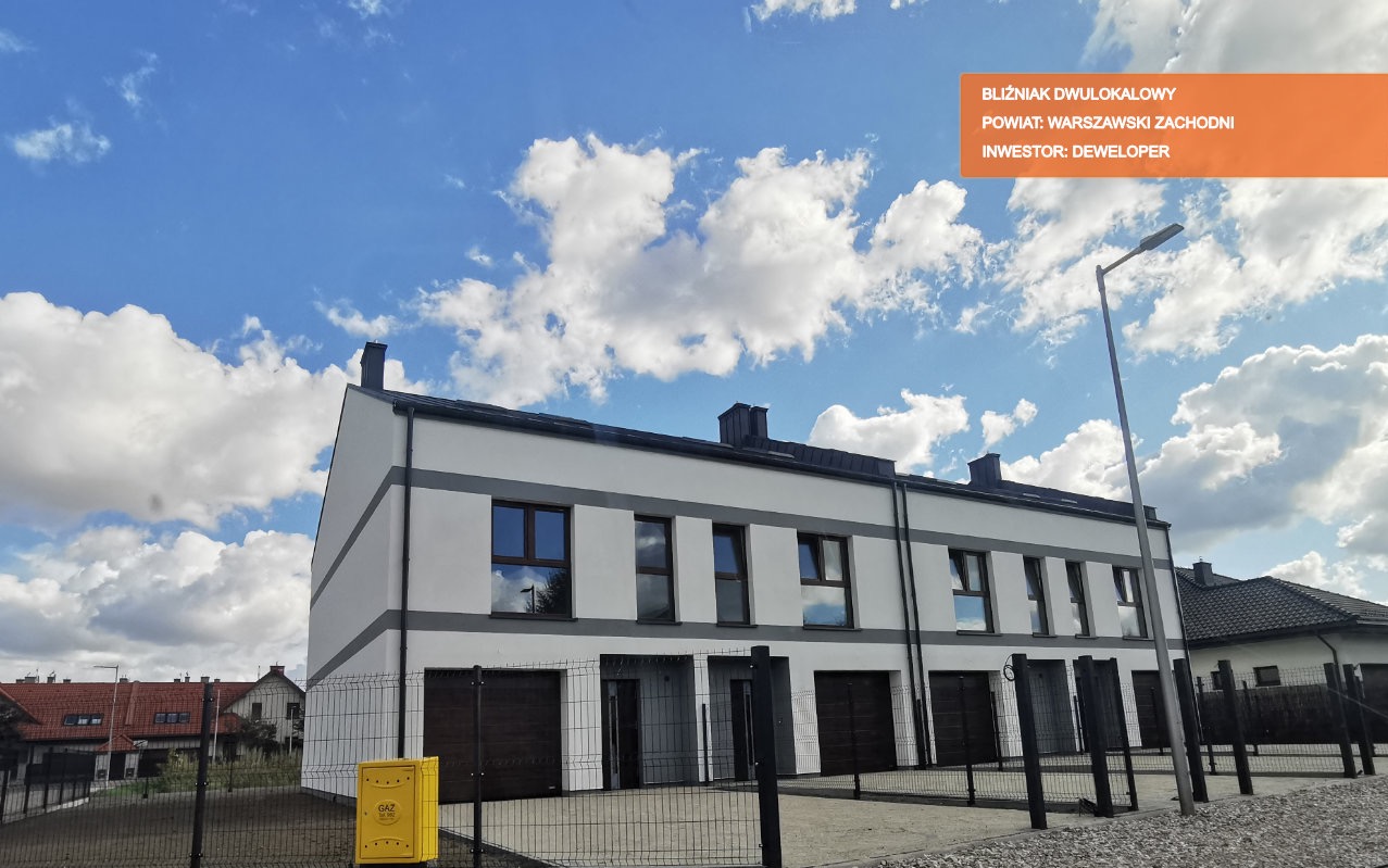 Nowoczesny budynek bliźniaczy z garażami, pomalowany na biało z szarymi akcentami, widoczny na tle błękitnego nieba z chmurami, z żółtą skrzynką gazową na pierwszym planie.