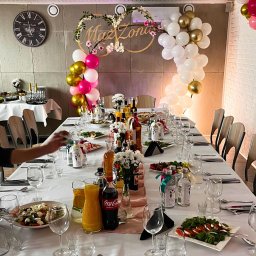 Restauracja Veneto - Uroczysty stół weselny z dekoracją balonową i napisem 'Mąż Żona', zastawiony potrawami, napojami i kwiatami, przygotowywany do przyjęcia gości.