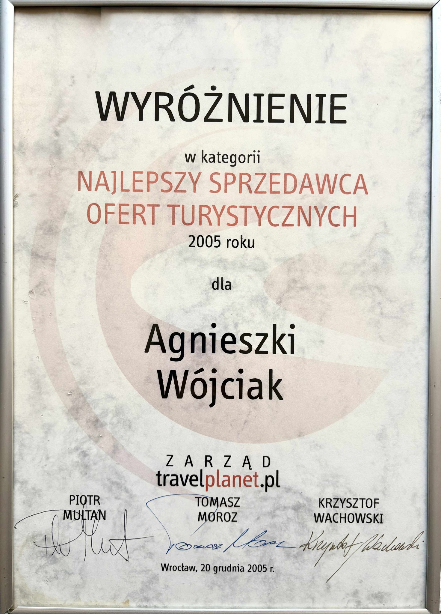 Dyplom z wyróżnieniem dla Agnieszki Wójciak jako najlepszego sprzedawcy ofert turystycznych w 2005 roku, przyznany przez travelplanet.pl. Sygnatury zarządu.