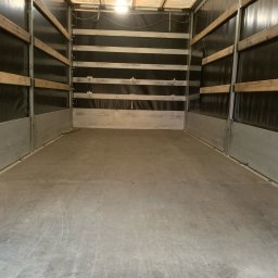 ERJOT CARGO Rafał Jastrzębski - Wnętrze pustej przestrzeni ładunkowej samochodu dostawczego z drewnianymi listwami zabezpieczającymi na ścianach i oświetleniem sufitowym