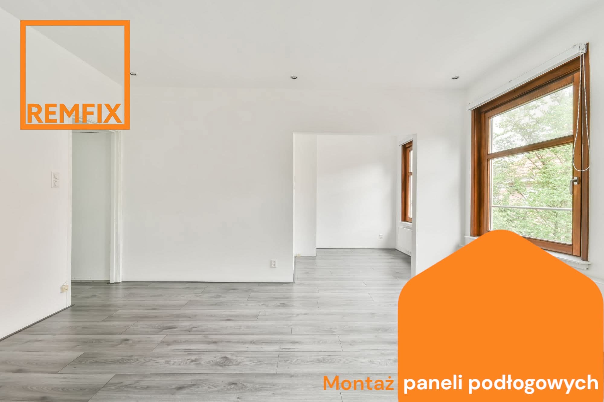 Jasne, przestronne wnętrze z szarymi panelami podłogowymi. Dwa okna z drewnianymi ramami wpuszczają światło dzienne. Świeżo wykończone, białe ściany i widoczne gniazdka elektryczne.