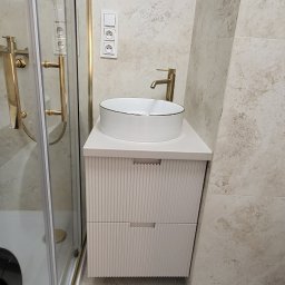 Ex-Mebel Marek Szpak - Nowoczesna łazienka z kabiną prysznicową ze złotymi detalami, umywalką nablatową z szafką w kolorze złamanej bieli i armaturą w odcieniu szczotkowanego złota.