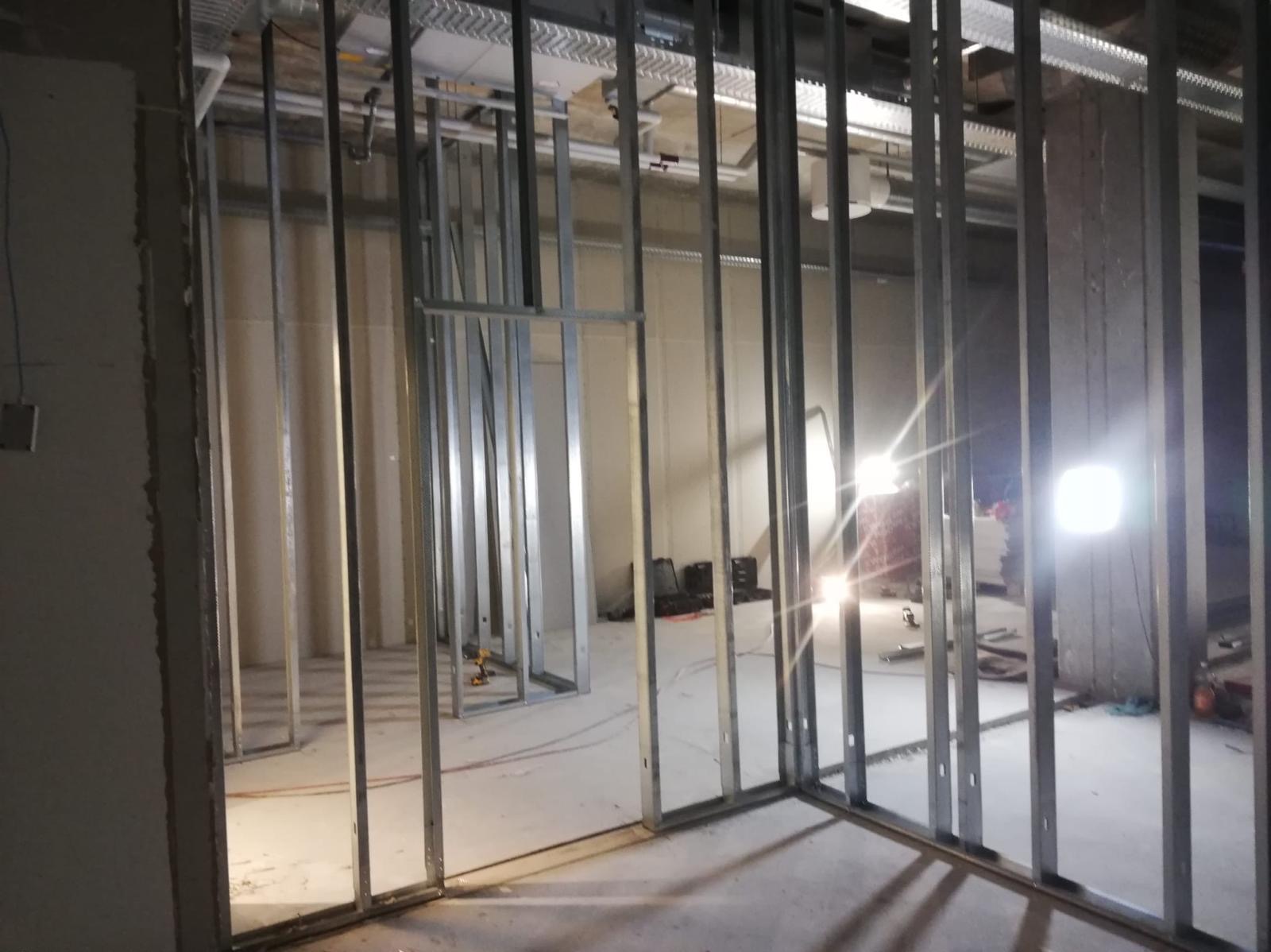 Metalowa konstrukcja szkieletowa ścian działowych w surowym stanie wewnątrz pomieszczenia, widoczne profile i mocowania, przygotowanie do montażu płyt gipsowo-kartonowych.