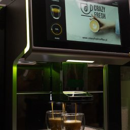 Crazy Fresh - Automatyczny ekspres do kawy z ekranem dotykowym podczas przygotowywania dwóch espresso w szklanych filiżankach.