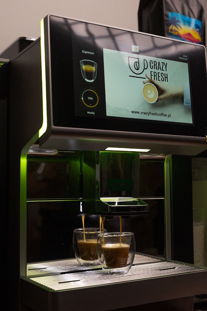 Automatyczny ekspres do kawy z ekranem dotykowym podczas przygotowywania dwóch espresso w szklanych filiżankach.