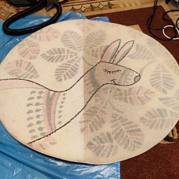 Lisa Pranie Mobilne OLEKSANDR LINTUR - Okrągły dywan dziecięcy z motywem lamy, widoczna różnica w czystości połowy dywanu po zabiegu czyszczenia, na podłodze z brązowym dywanem.