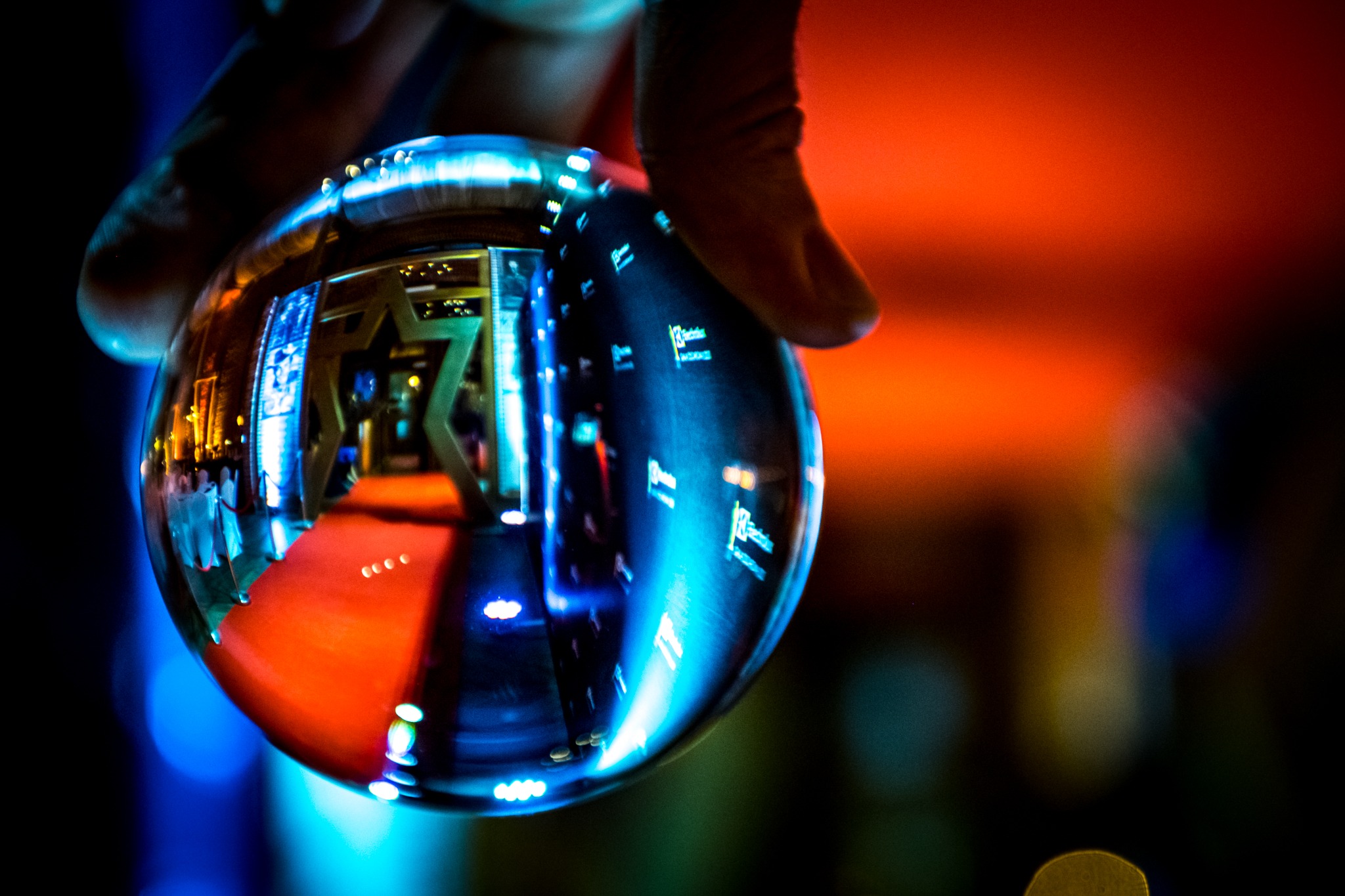 Szklana kula w dłoni odbija czerwony dywan, gwiazdę i światła eventu. Unikalne ujęcie z perspektywy fotografa eventowego, z rozmytym tłem.