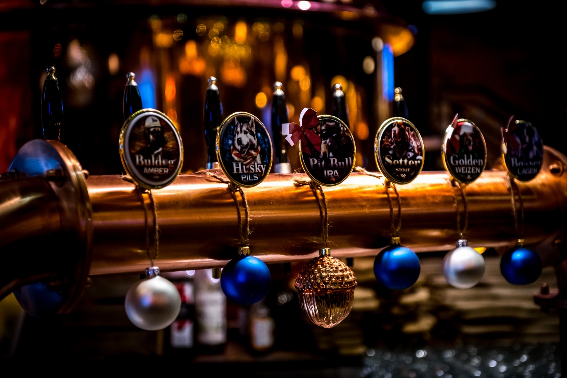 Mosiężny kran z różnymi rodzajami piwa, ozdobiony świątecznymi bombkami. Widoczne nazwy piw: Buldeo, Husky, Pit Bull, Setter, Golden, Bosser.