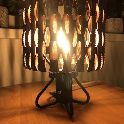 WANDZEL CUSTOM MICHAŁ WANDZEL - Ręcznie robiona lampka nocna z metalowym ażurowym kloszem i podstawą z czarnej liny, oświetlona ciepłym światłem żarówki, stoi na drewnianym blacie.