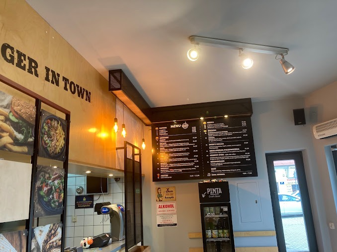 Wnętrze lokalu Burger In Town: menu na ścianie, oświetlenie, zdjęcia potraw w ramkach, bar z dystrybutorem napojów, chłodziarka z napojami Pinta Craft Beer.