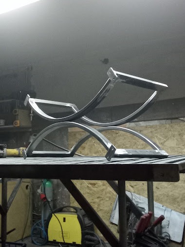 Metalowy stelaż krzesła w trakcie produkcji, widoczne spawane elementy i narzędzia w warsztacie.