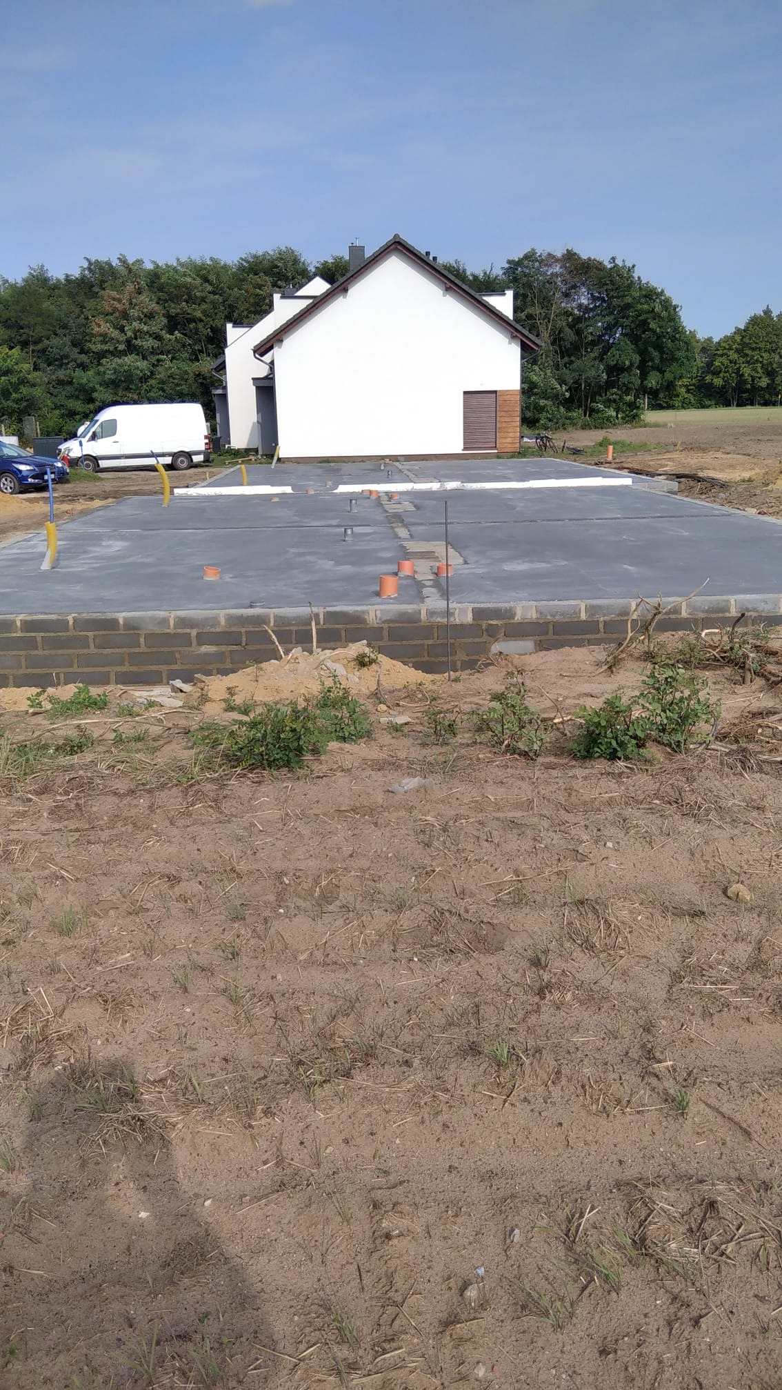 Fundamenty domu jednorodzinnego z izolacją poziomą i pionową, widoczne instalacje w Gronówko. Etap budowy przed wylaniem płyty fundamentowej.