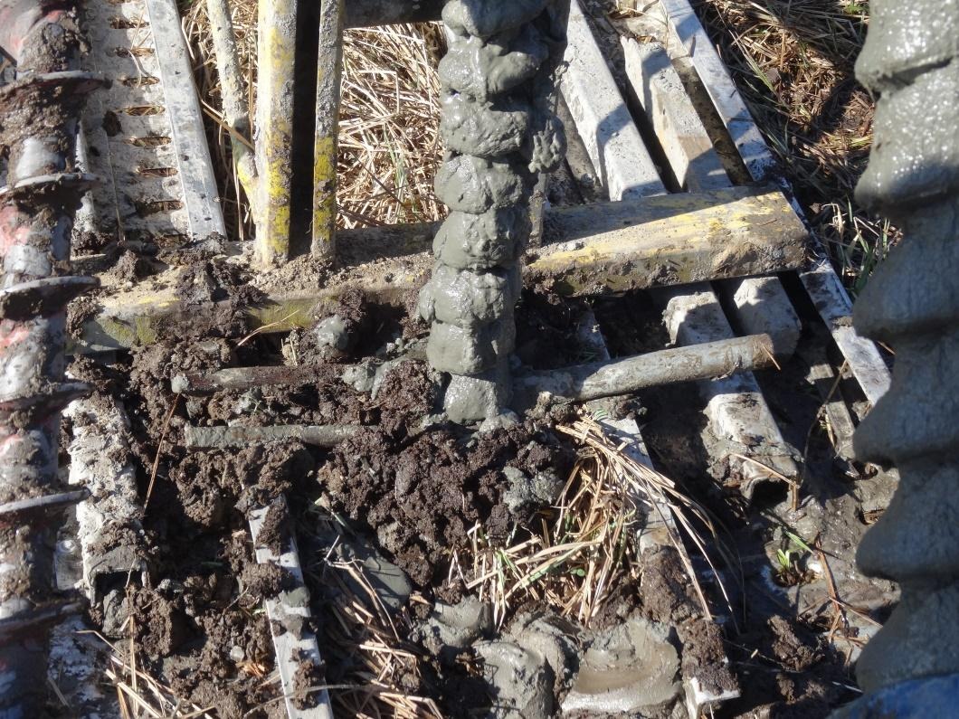 Wiercenie i zalewanie betonem otworu w gruncie, widoczne zbrojenie i mokra ziemia.