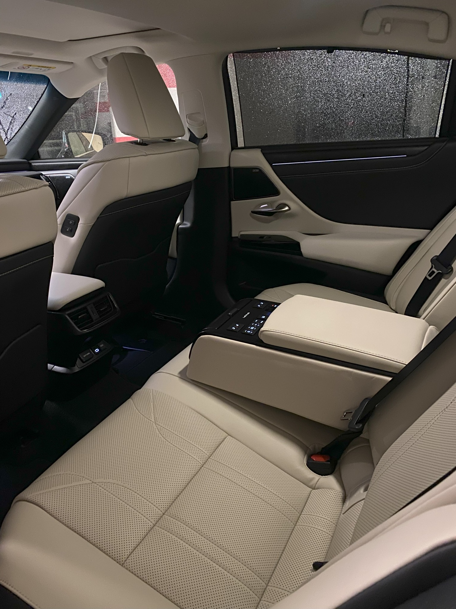 Wnętrze samochodu z beżową skórzaną tapicerką, widok z tyłu na podgrzewane fotele, rolety przeciwsłoneczne w oknach i złącza USB-C. Komfortowa podróż.