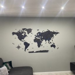 Ściany pomalowane w kolorze oraz montaż mapy świata z drewna na ścianie.