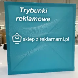 Niebieski trybunek reklamowy z białym napisem 'Trybunki reklamowe' i adresem strony internetowej, na tle hali produkcyjnej.