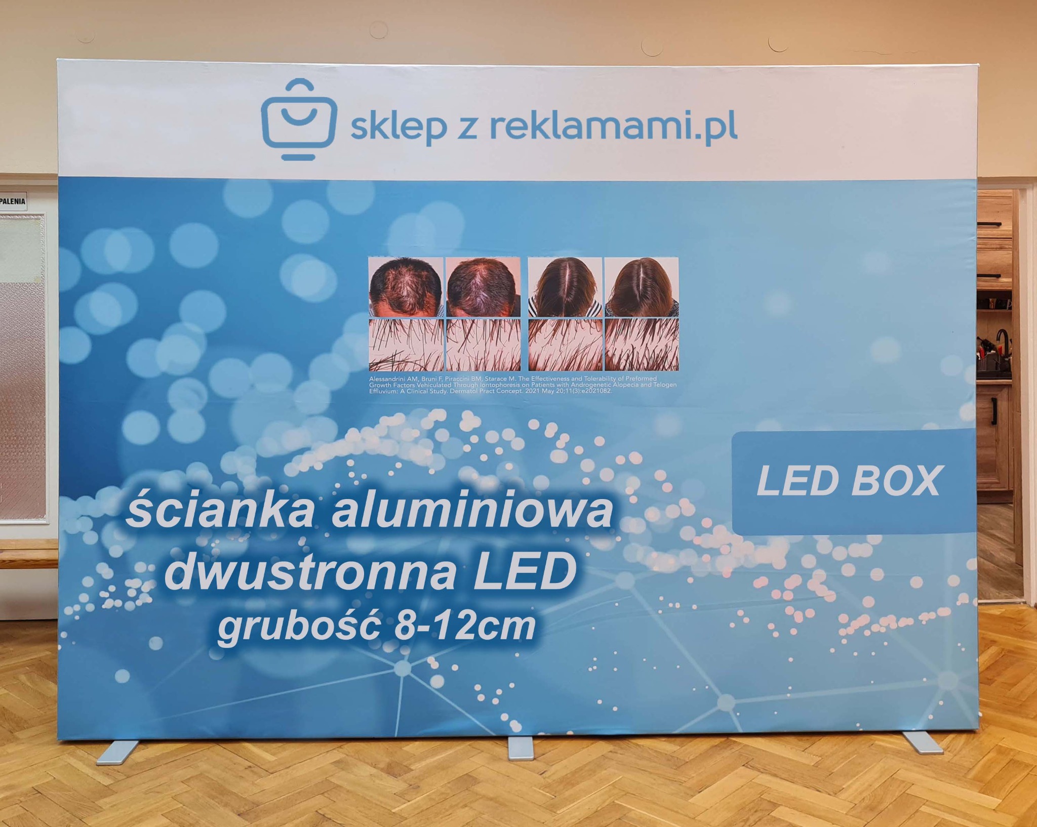 Aluminiowa ścianka reklamowa dwustronna LED z grafiką prezentującą efekty leczenia wypadania włosów, z adresem sklepu z reklamami w górnej części.
