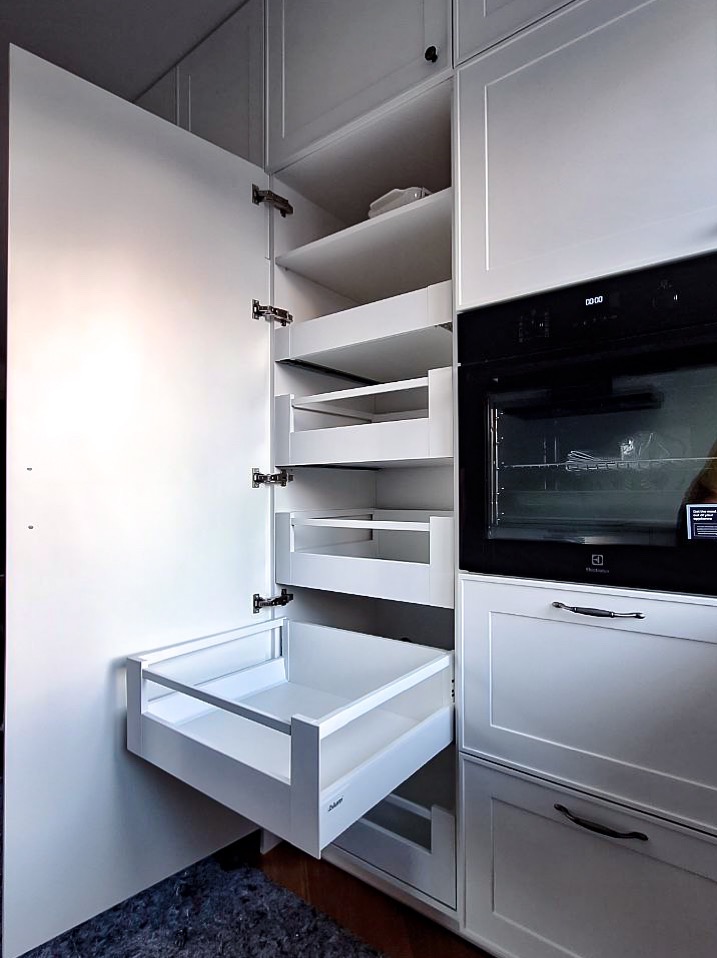 Biała zabudowa kuchenna z wysuwanymi półkami i piekarnikiem Electrolux. Otwarta szafka z systemem cargo. Nowoczesny design, funkcjonalne rozwiązanie do przechowywania.