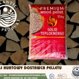 Worek pelletu drzewnego premium 15kg marki Solid Teploenergo na tle pociętego drewna. Widoczne logo Atlantic Agro Produkt i dane kontaktowe dostawcy.