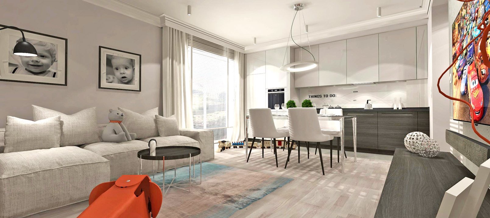 Wnętrze mieszkania z otwartą kuchnią i salonem. Na ścianie wiszą zdjęcia dziecięce, a na podłodze leży pomarańczowa zabawka. Widoczny stół z krzesłami i telewizor.